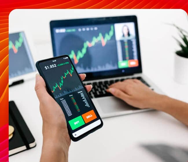 A person analyzing stock market charts on a laptop and smartphone.